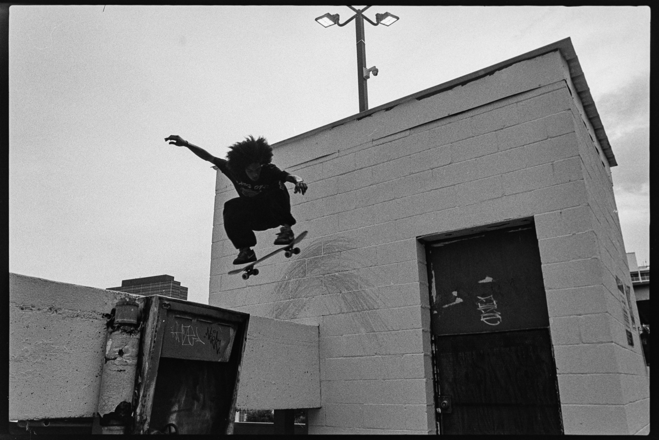 Skateboarder airborne over a New Orleans rooftop wall