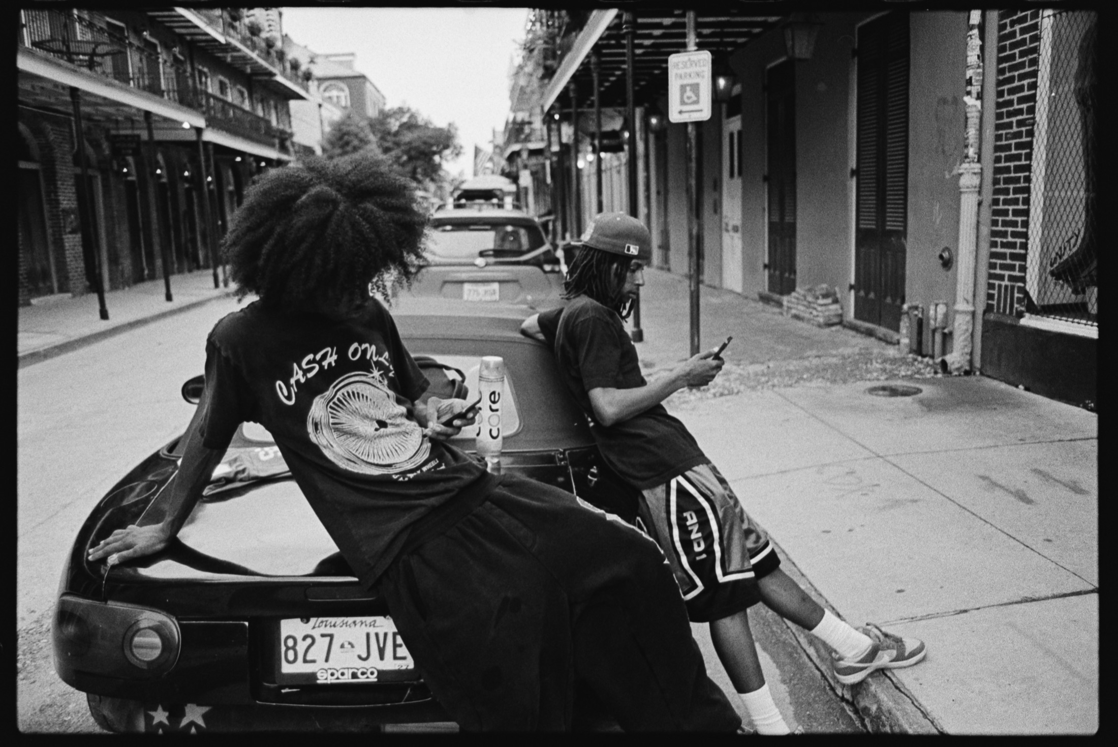 Two friends leaning against a car in New Orleans